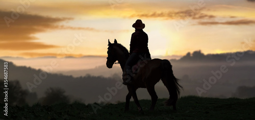 a silhouette rider on Horse at sunrise in the background.