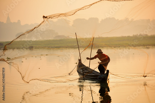 Foto Local fisher man use fish net catch fish in Taungthaman lake near u-bein bridge,