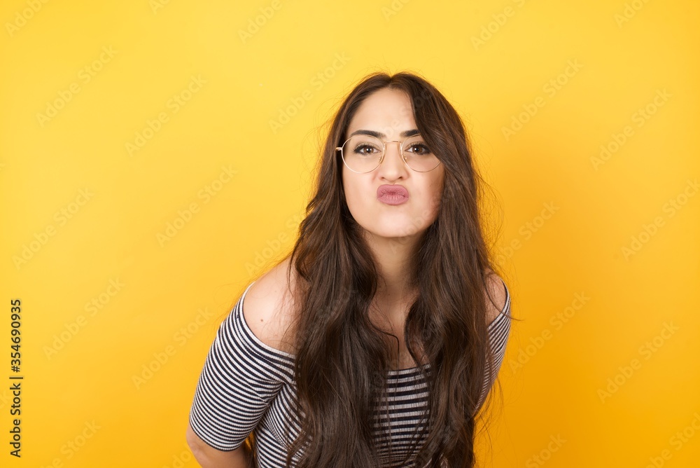 Pleasant looking young female, keeps lips as going to kiss someone, has glad expression, grimace face. Standing outdoors. Beauty concept. Pleasant looking young female, keeps lips as going to kiss someone, has glad expression, grimace face. Standing outdoors. Beauty concept.