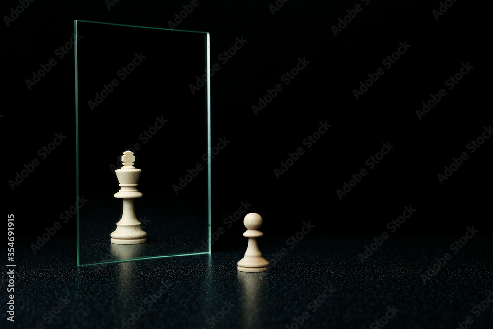 reassessment of their abilities. the pawn is reflected in the mirror like a king on black background - obrazy, fototapety, plakaty 
