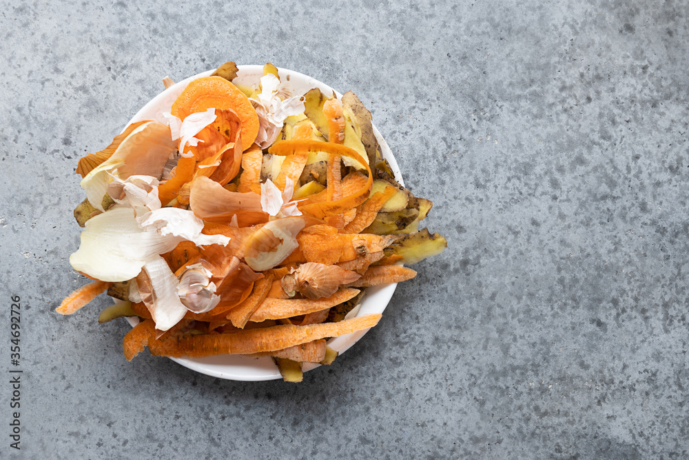 Peel from different vegetable peeling in white plate. Organic waste from food. View from above. Space for text.