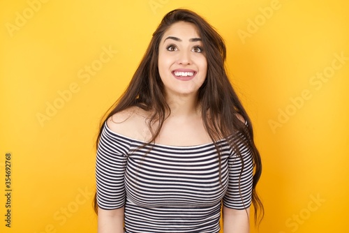 People and sudden reaction concept. Surprised caucasian beautiful female student, shrugs shoulders, looking sideways, being happy and excited about new plans with friends. Isolated over gray wall.