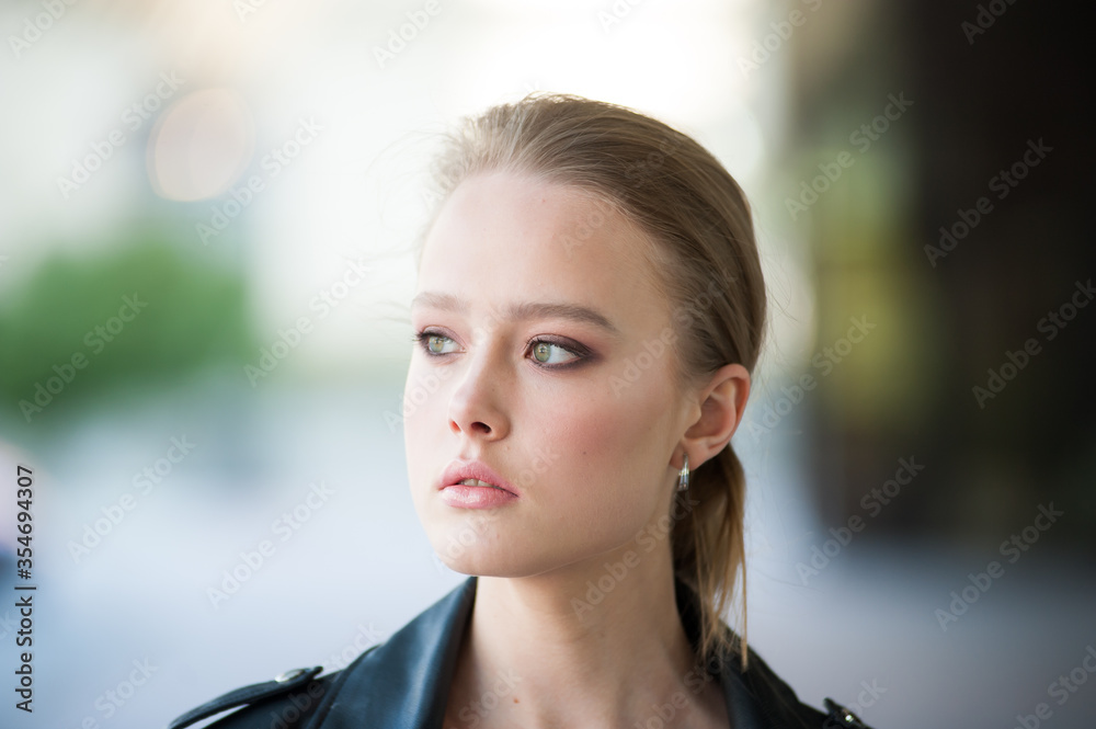 Obraz premium Beautiful young blonde woman in a leather jacket outside