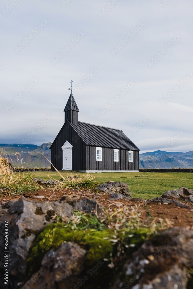 Black church in the meadow and field in Iceland. Icelandic scenic travel destination of religion. Christianity and religious concept. Postcard theme. Praying in chapel.Mountains on background. Black church in the meadow and field in Iceland. Icelandic scenic travel destination of religion. Christianity and religious concept. Postcard theme. Praying in chapel.Mountains on background.