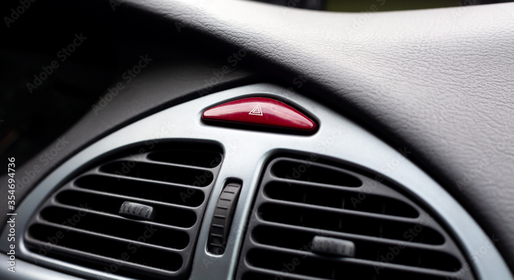 Simple red hazard warning lights button on car dashboard, triangle pictogram closeup, detail shot. Vehicle safety light alert signal, transportation hazard light switch concept