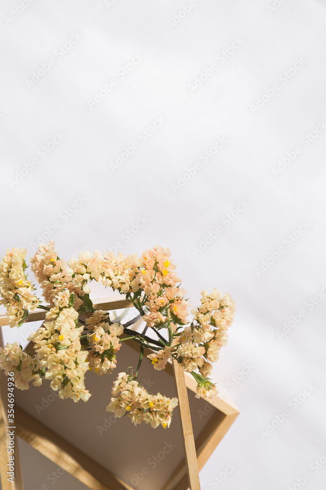 Top view of a wooden niche in voile fabric background with flowers, with space for text. Vertical Top view of a wooden niche in voile fabric background with flowers, with space for text. Vertical