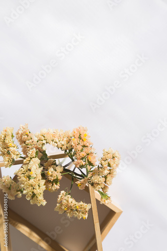 Top view of a wooden niche in voile fabric background with flowers, with space for text. Vertical