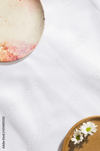 Top view of white flowers in a plate and a empty plate in voile fabric background with space for text.