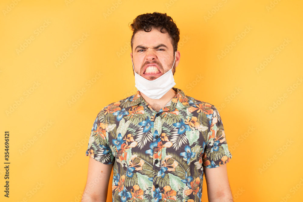 Portrait of angry male has own style of clothing, keeps teeth clenched, frowns face in dissatisfaction, irritated because of much duties. Furious man looks out of window, sees miserable weather Portrait of angry male has own style of clothing, keeps teeth clenched, frowns face in dissatisfaction, irritated because of much duties. Furious man looks out of window, sees miserable weather