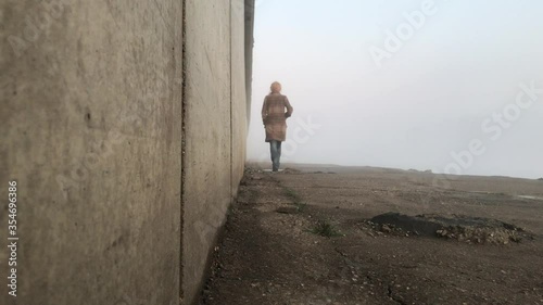 The girl goes into the distance. Around the fog. Deserted embankment in the evening fog.