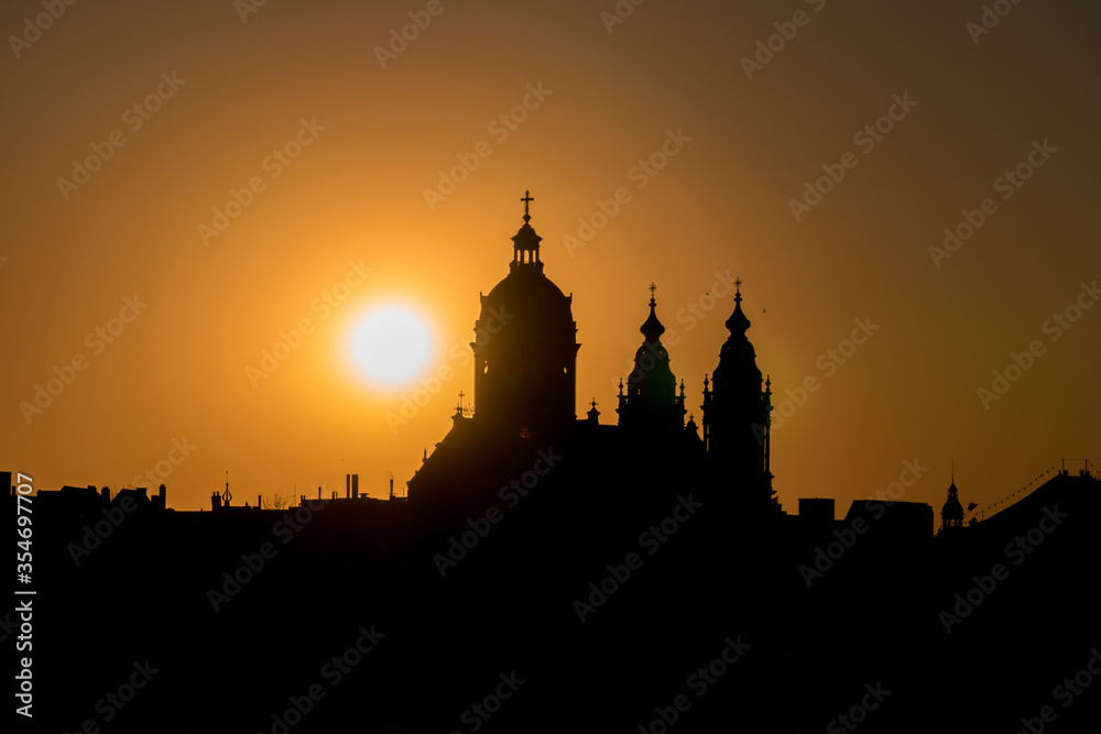 Neo-Baroque Basilica of Saint Nicholas silhouette at the sunset against orange sky with a sun setting behind in Amsterdam