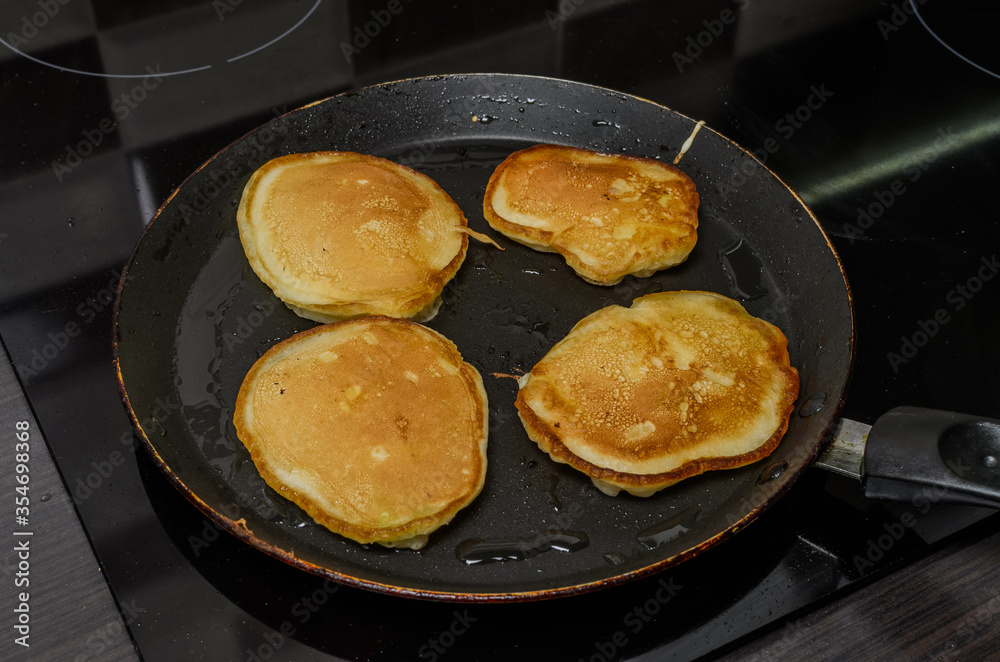 Pancakes are fried in a pan on an induction stove