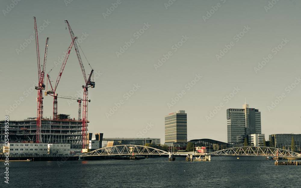 Amsterdam industrial area skyline with red cranes , high office buildings , water  - developing area 