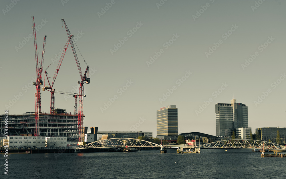 Amsterdam industrial area skyline with red cranes , high office buildings , water - developing area Amsterdam industrial area skyline with red cranes , high office buildings , water - developing area