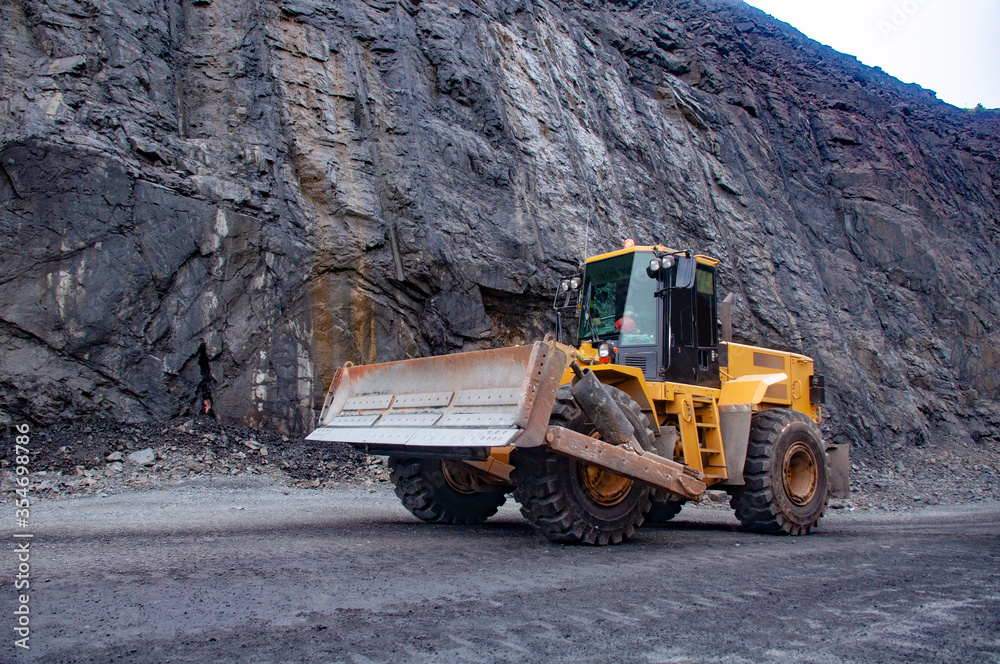 mountain loader in an iron ore quarry. Mining loader. Mountain loader on the background of the side of the quarry mountain loader in an iron ore quarry. Mining loader. Mountain loader on the background of the side of the quarry
