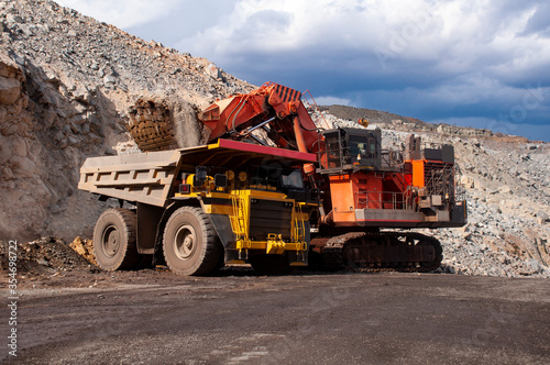 Excavator in the quarry loads the dumper with iron ore.