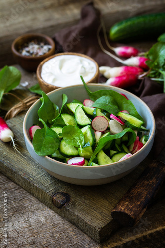 Healthy vegan food. Vegetarian vegetable salad of spinach, radish and fresh cucumber. Copy space.