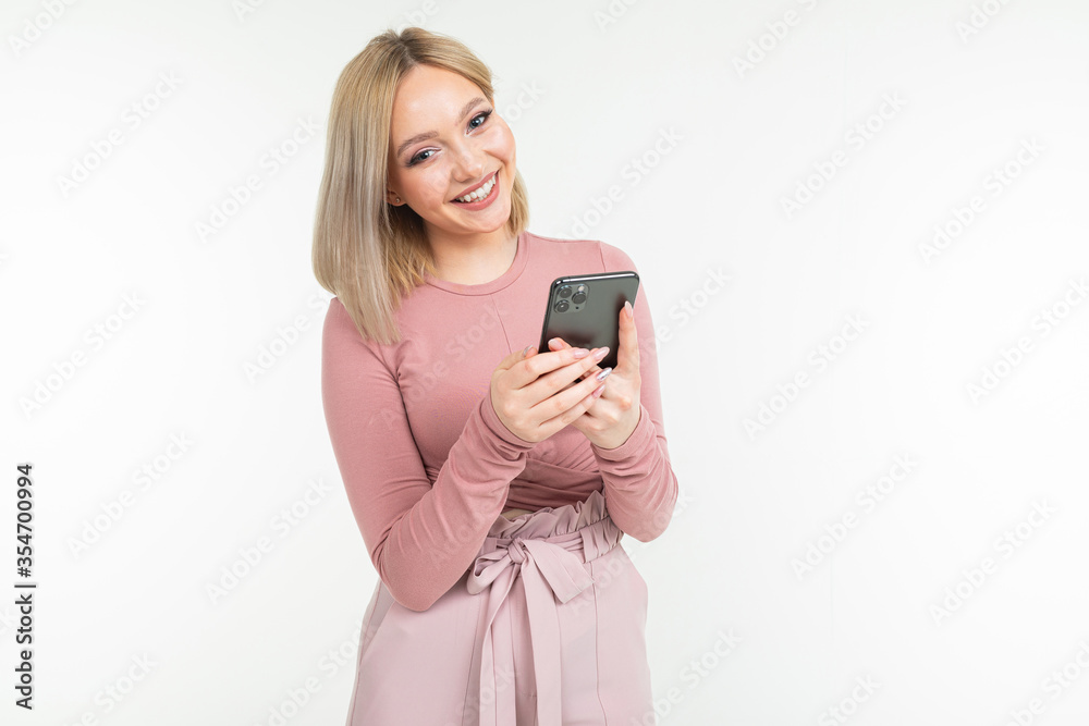 smiling girl in pink clothes surfing the internet on the phone on a white background smiling girl in pink clothes surfing the internet on the phone on a white background