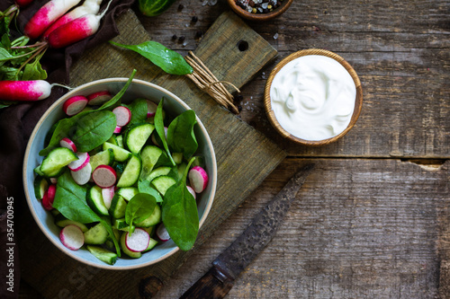 Healthy vegan food. Vegetarian vegetable salad of spinach, radish and fresh cucumber. Top view flat lay background. Copy space.