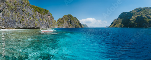 Banca boat moored near limestone rocks of Matinloc island, highlights of hopping trip Tour C. Most beautiful place at Marine National Park, Palawan