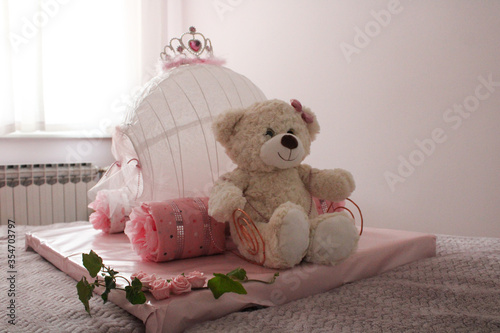 MAY 28: Baby shower gift. White teddy bear with pink carriage on bed. Indoors