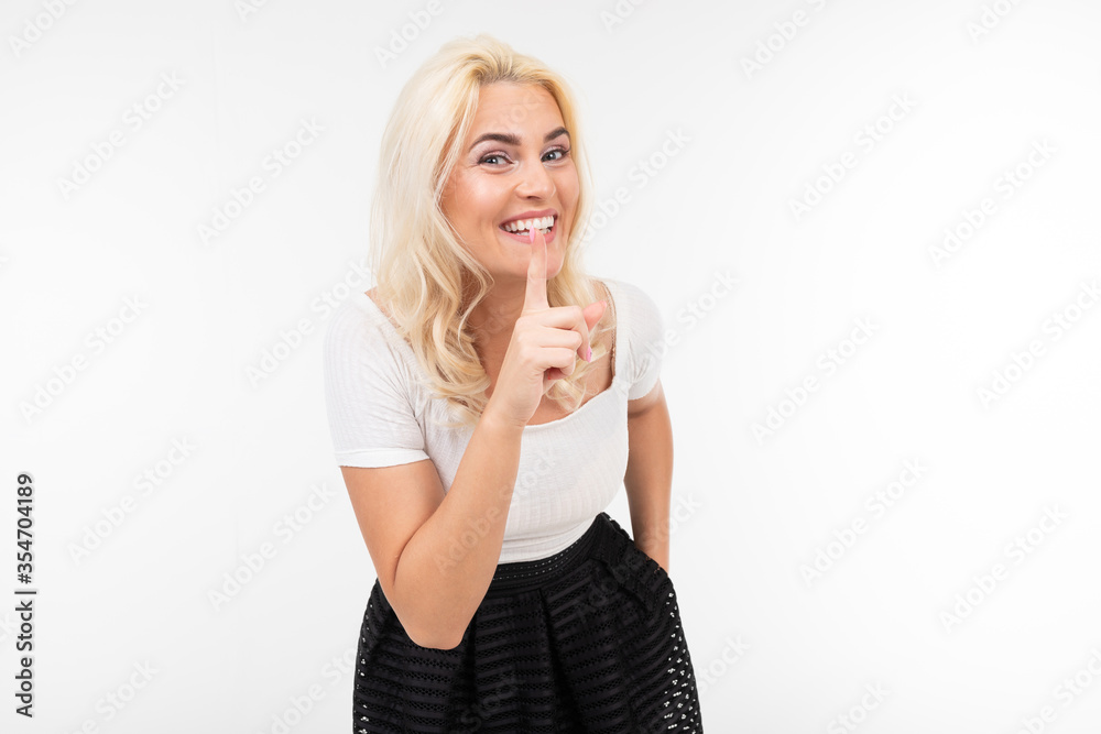 girl asks to be silent while holding a finger at her mouth on a white studio background girl asks to be silent while holding a finger at her mouth on a white studio background