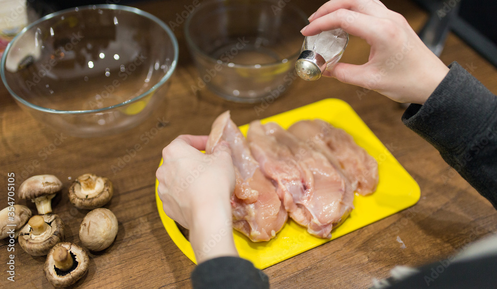 woman cooking chicken meat on yellow desk at kitchen