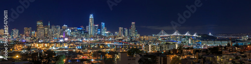 San Francisco skyline night panorama with city lights, the Bay Bridge and light trails on the highway