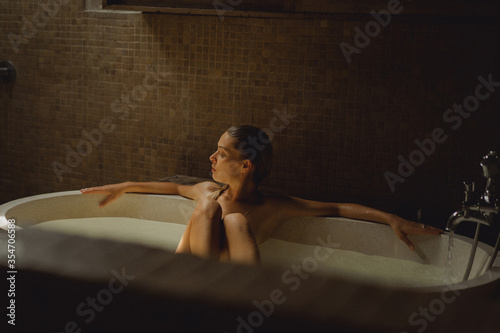 Beautiful smiling Caucasian woman posing with wet hair at bathroom, relaxing in the bath in the bathroom. young woman lying in bathtub. .woman taking a bath, personal care photo