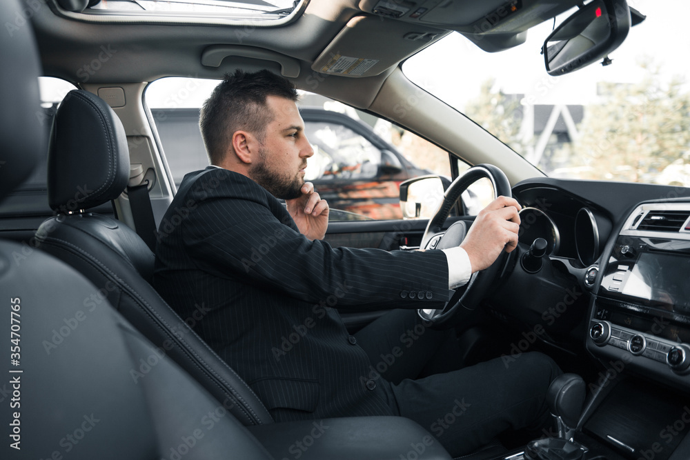 Handsome caucasian businessman driver inside in vehicle  with coffee and gadget and check mail and talking with partners