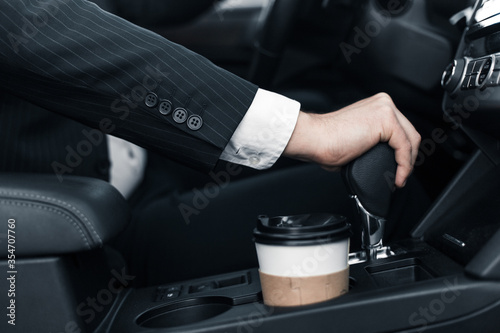 Handsome caucasian businessman driver inside in vehicle  with coffee and gadget and check mail and talking with partners © klepach