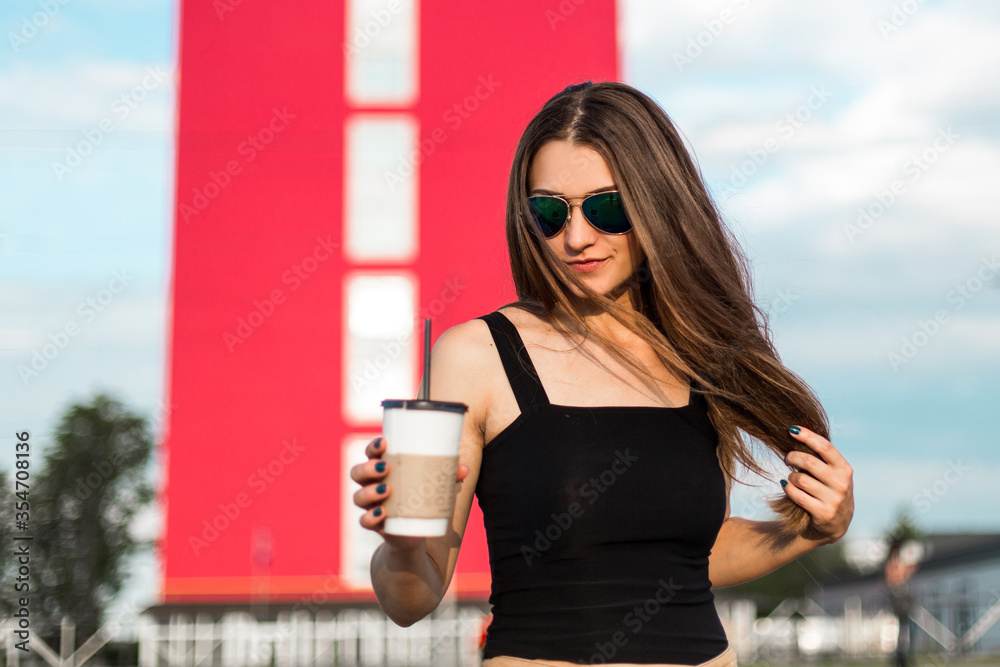 Obraz premium Happy young woman drink coffee walking on the street.