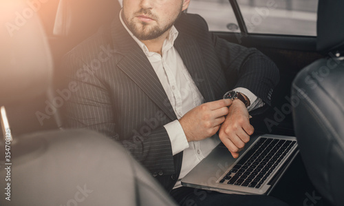 Handsome caucasian businessman driver inside in vehicle  with coffee and gadget and check mail and talking with partners © klepach