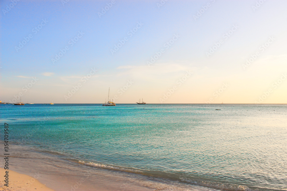 Beach in the ocean with blue water and fine sand. On the garisont, boats and yachts are visible. The sun at sunset. So want to plunge. Aruba August 2014 Beach in the ocean with blue water and fine sand. On the garisont, boats and yachts are visible. The sun at sunset. So want to plunge. Aruba August 2014