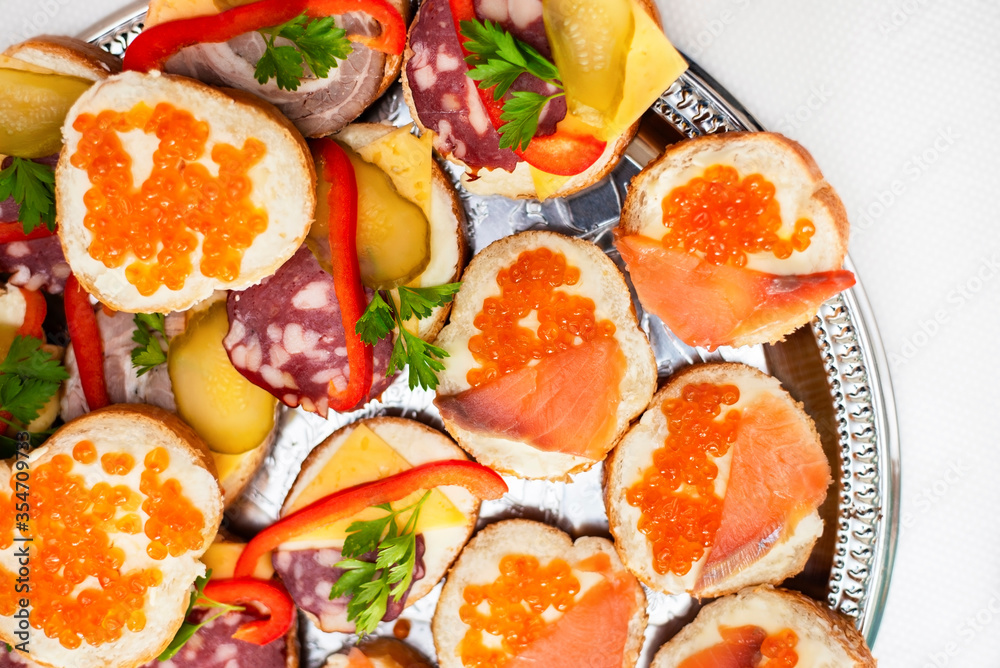 Delicious sandwiches with red fish and salmon caviar and herbs, there are sandwiches with sausage. Flat lay Delicious sandwiches with red fish and salmon caviar and herbs, there are sandwiches with sausage. Flat lay