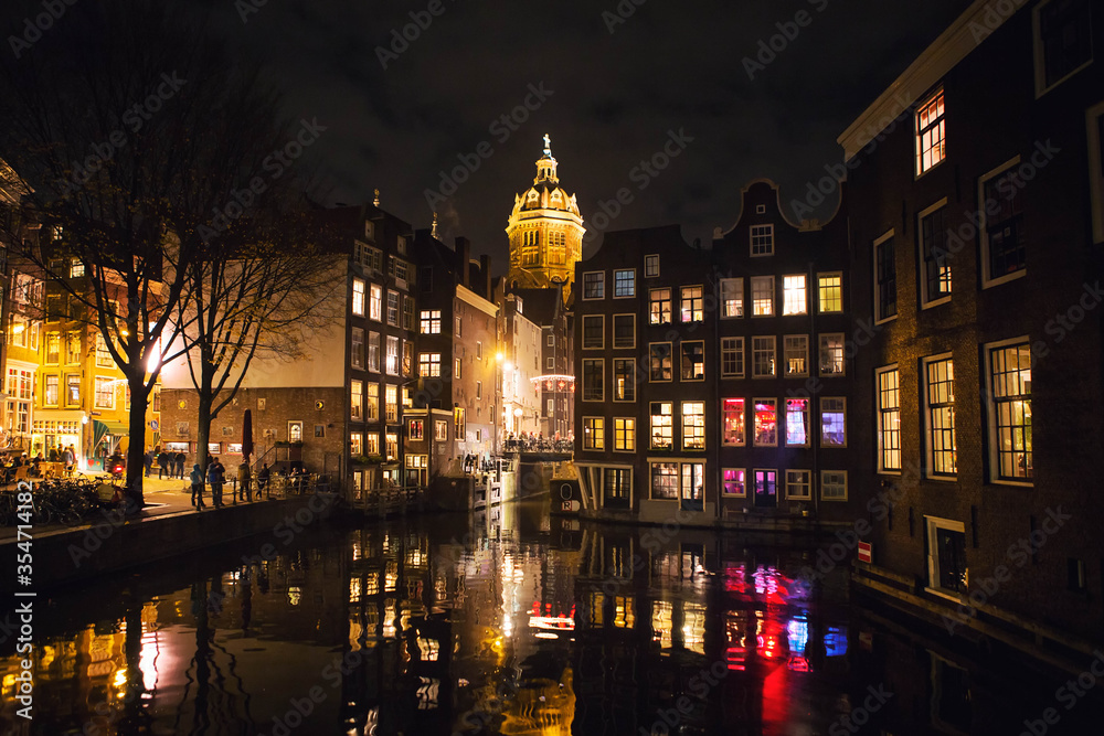 Night view of Amsterdam city with canal and Basilica of Saint Nicholas,  famous landmark view from the Armbrug bridge, Netherlands, Holland, Europe.