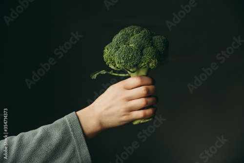 Man holding broccoli in his hand on a gray background