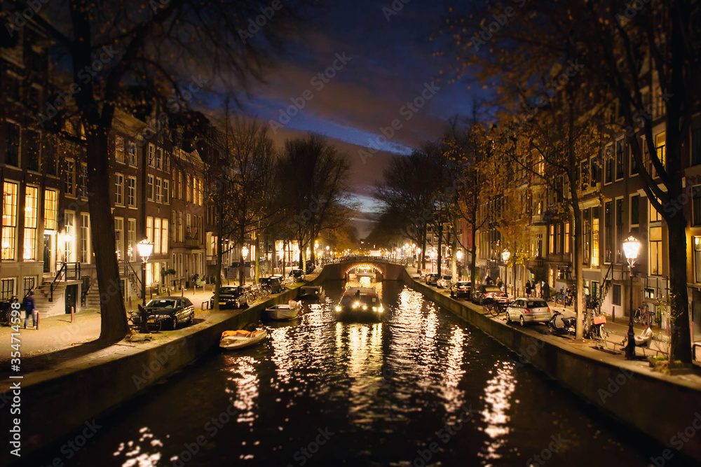 Characteristic view of a canal illuminated at dusk in Amsterdam city center. Netherlands, Holland, Europe.