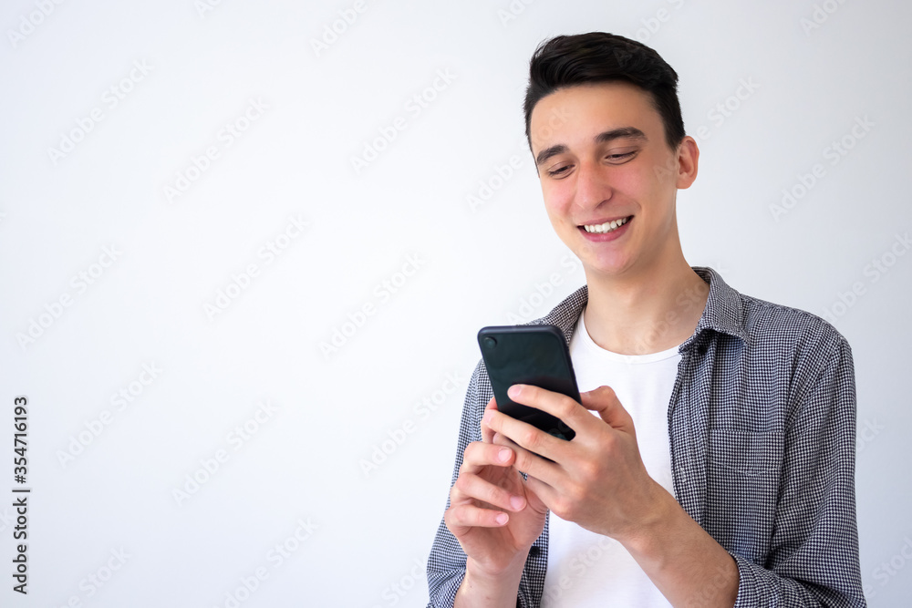 a positive, happy guy communicates in messengers via phone. Guy on a gray background. Copy space a positive, happy guy communicates in messengers via phone. Guy on a gray background. Copy space