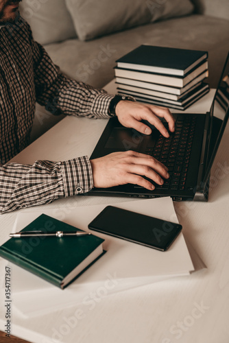 Business space, man in shirt prints on laptop, notebook, papers, phone on the side