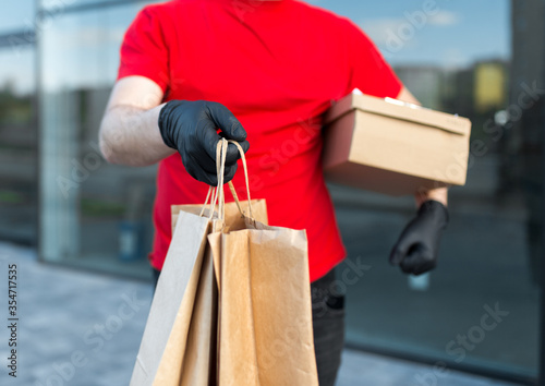 Young delivery man with package in medical mask and gloves