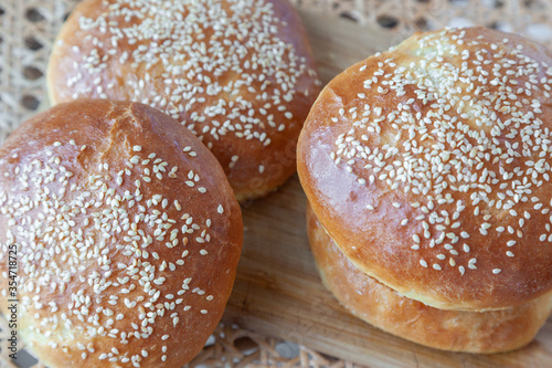 Three appetite burger buns with sesame seeds on top  on ratten table © Andrei Pogrebnoi