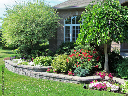 Landscape design with multiple levels and stone retaining wall for flower beds.