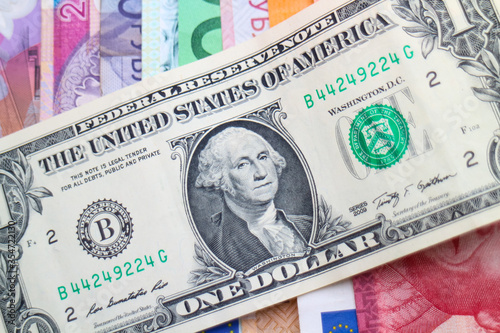 US Dollar banknote arranged diagonally on a pile of rainbow banknotes of different world currencies, including Euro notes, Australian Dollars, Israeli Shekels, South African Rand and Polish Złoty. 