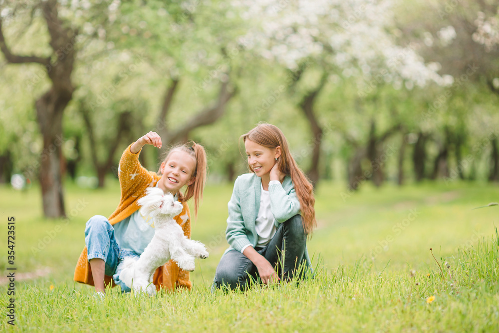 Little smiling girls playing and hugging puppy in the park
