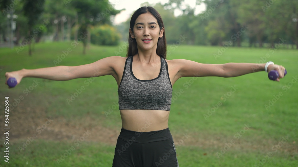 Holiday concept. Young women practicing lifting dumbbells in the garden. 4k Resolution. Holiday concept. Young women practicing lifting dumbbells in the garden. 4k Resolution.