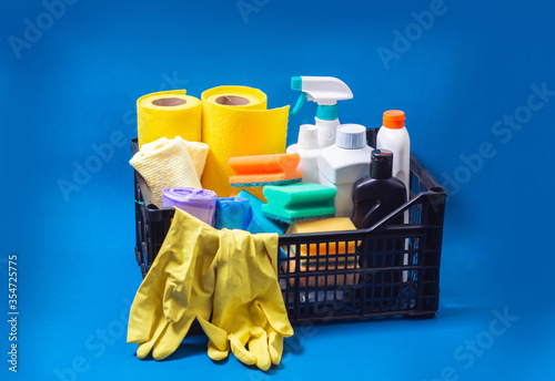 Home cleaning supplies in box on blue background. Indoor cleaning concept