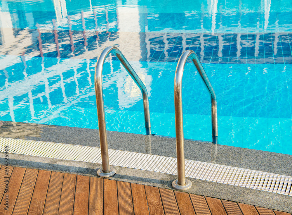 Grab bars ladder in the blue swimming pool Grab bars ladder in the blue swimming pool