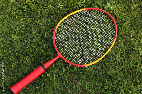 Badminton racket on green grass background