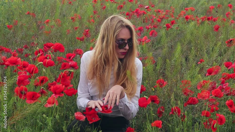 4K video blonde in sunglasses and a white shirt on a field with blooming poppies 4K video blonde in sunglasses and a white shirt on a field with blooming poppies